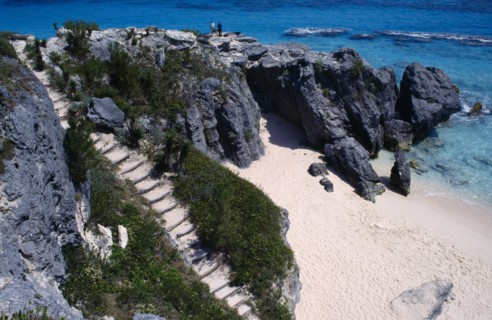 BERMUDA, Warwick, Astwood Park, Two people standing on cliff top above empty sandy beach with steps
