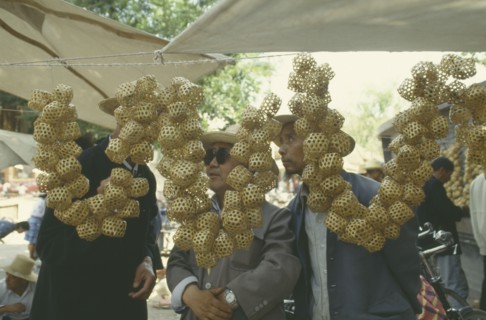 CHINA, Linxia, Buyers looking at  Woven bamboo cricket cages strung together and hung up on a stall