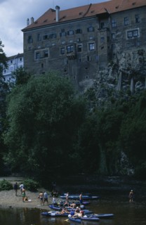 CZECH REPUBLIC, South Bohemia, Cesky Krumlov, Canoeists relaxing on a river side with the Chateaux
