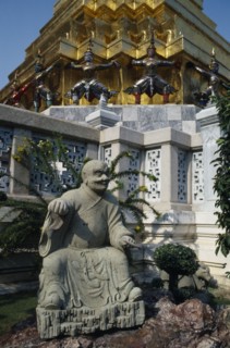 THAILAND, Bangkok, Grand Palace, Aka Wat Phra Kaeo. Stone statue on rockery next to small tree in