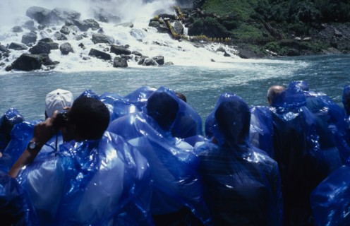 CANADA, Ontario, Niagara Falls, Maid of the Mists tourists in blue waterproofs looking toward