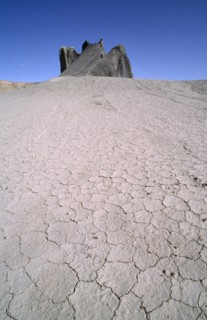 USA, Utah, North Pinto Hills, View over cracked dry earth toward rock formation on the horizon