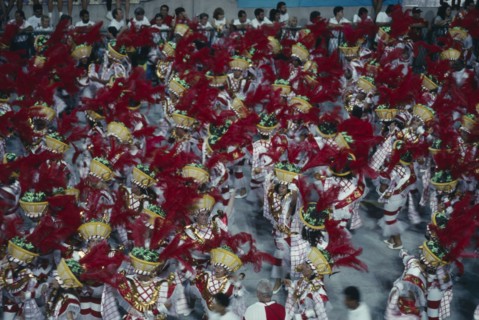 BRAZIL, Rio de Janeiro, Carnival procession of dancers wearing red feathered head dresses