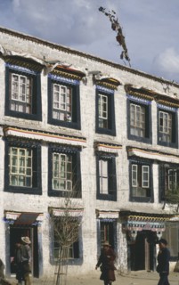 CHINA, Tibet, Lhasa, Traditional houses with ribbons hanging above the windows and people walking