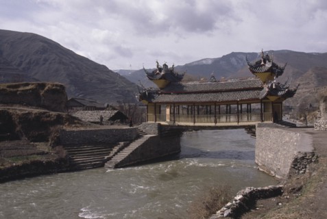 CHINA, Sichuan Province, Songpan, Chinese bridge with pagoda style roof over river in mountain