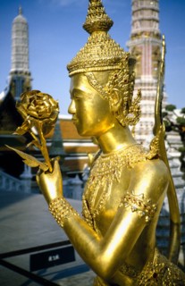 THAILAND, Bangkok, Wat Phra Kaew, Or Royal Palace. Golden temple statue of a figure holding a