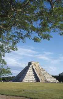 MEXICO, Yucatan, Chichen Itza, "El Castillo, angled view of facade partly framed by tree branches