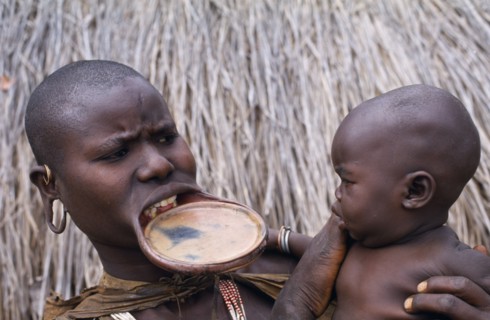 ETHIOPIA, Western Highlands, Children, Surma woman with lip plate holding baby.