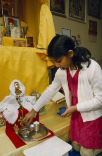 ENGLAND, Religion, Hindu, Young girl kneeling on floor preparing shrine for prayer.