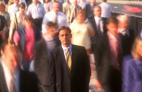 BUSINESS, Commuters, City businessman in suit standing motionless surrounded by crowds in blurred