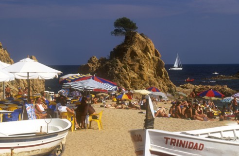 SPAIN, Catalonia, Platja de la Mar Menuda, Busy sandy beach with people sitting at tables under