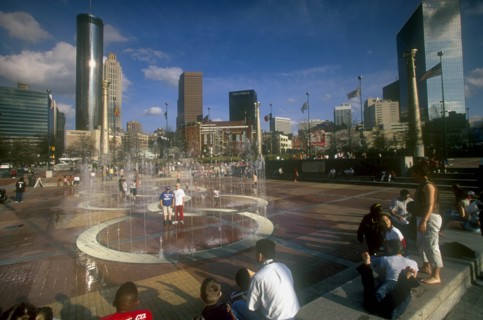 USA, Georgia, Atlanta, "Centennial Olympic Park.  Visitors around paved area with fountains, city