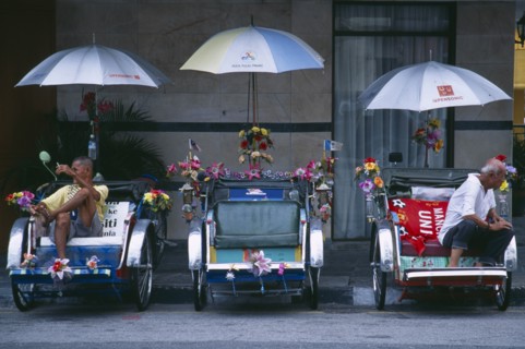 MALAYSIA, Penang, Georgetown, General.  Street scene with three bicycle rickshaws decorated with