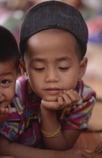 THAILAND, North, Mae Sai, Burmese Karen refugee child in camp looking down with his chin in his