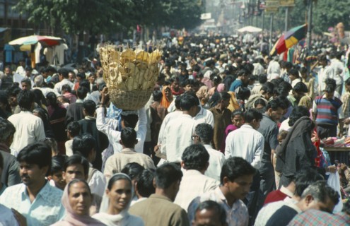 INDIA, General, Crowded street scene with man in centre carrying basket of bread on his head.
