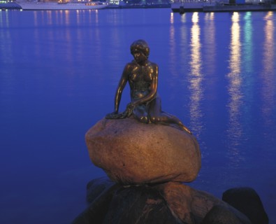 DENMARK, Zealand, Copenhagen, The Little Mermaid statue at night with lights reflected in the water