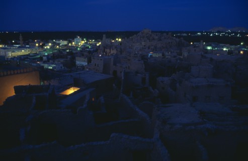EGYPT, Western Desert, Siwa Oasis, View across town towards Shali Fortress at night with oasis in