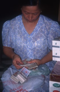 VIETNAM, Hanoi, Seated woman counting out bank notes.