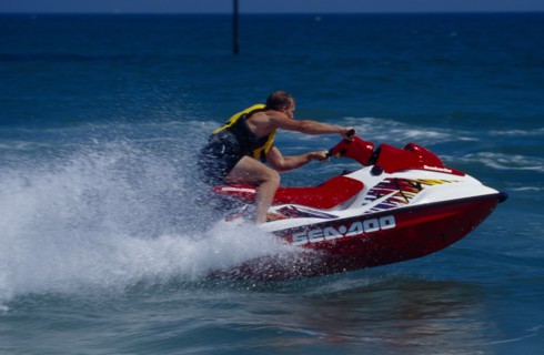 20002911 SPORT Watersports Jet Ski Man riding a jet ski on the sea at Littlehampton in West Sussex  England.  Viewed from the side.