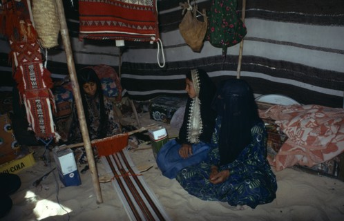 QATAR, People, Bedouin girls sitting inside tent decorated with hanging textiles weaving
