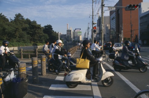 JAPAN, Shikoku, Matsuyama, Commuters on scooters and bicycles waiting to cross road.