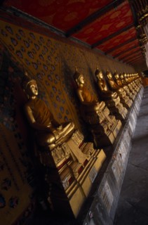 THAILAND, Bangkok Area, Bangkok, Wat Arun. Golden seated Buddha statues in cloister of Ordination