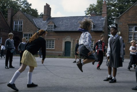 ENGLAND, Birmingham, Primary schoolchildren playing skipping games in playground.