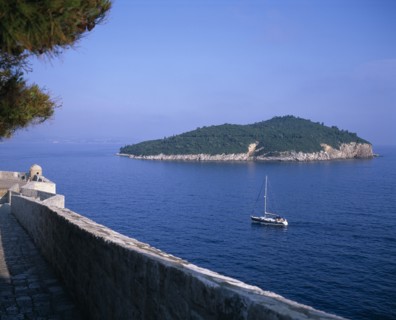 CROATIA, Dalmatia, Dubrovnik, Boat sailing between the City Walls or Gradske Zidine and Kolocep