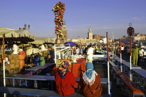 MOROCCO, Marrakech, Djemaa El Fna. Food stall with two customers seated in the foreground
