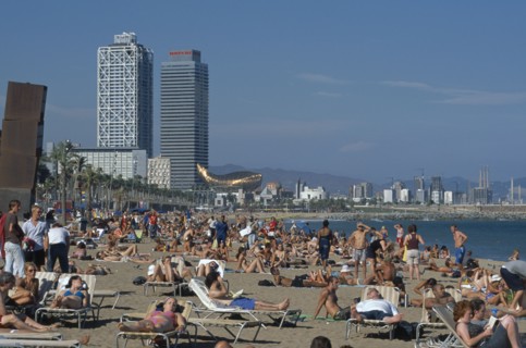 SPAIN, Catalonia, Barcelona, Vila Olimpica area.  Crowded sandy beach with wire mesh monument by