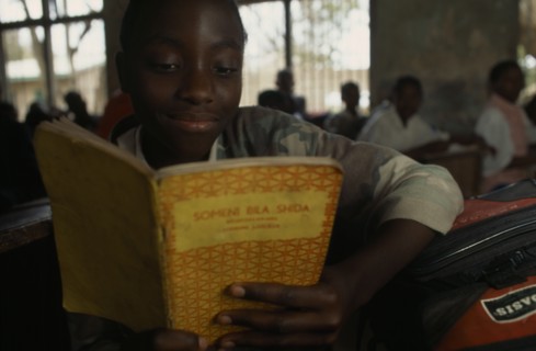 TANZANIA, Shinyanga, Mwenge Primary School child reading a text book in the classroom