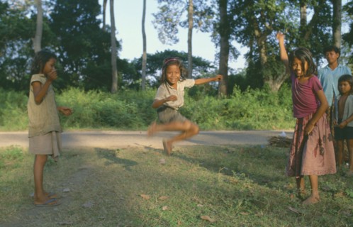 CAMBODIA, Angkor, Young girls with skipping rope playing beside road.