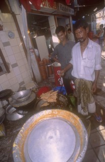 BANGLADESH, Dhaka, Street side shop preparing sweet  snacks for Iftar. The sunset breaking off the