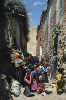 NEPAL, Mustang, Ghemi, People carry sacred texts through narrow street for the Lok Khor festival