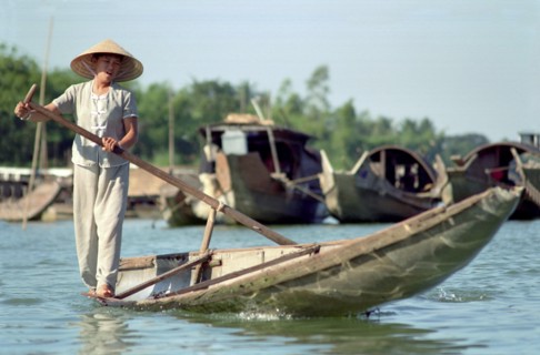 VIETNAM, Central, Hue, Local transport woman standing on the edge of her canoe rowing with a single