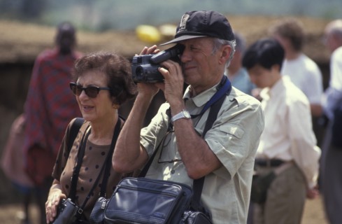 KENYA, , An American tourist films in a cultural manyatta set up to interface the Maasai directly