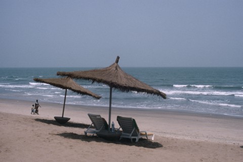 GAMBIA, People, Hotel beach front with woman and child walking hand in hand over sand. Sun loungers