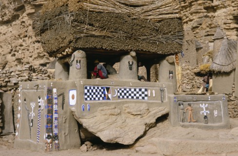 MALI, Bandiagara Cliffs, Newly painted Dogon Toguna or meeting place with men sitting on raised