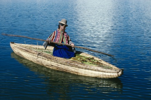 PERU, Puno, Lake Titicaca, Uros woman on reed boat rowing to floating island.