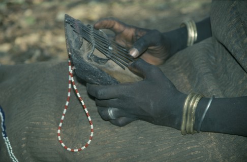 ETHIOPIA, Music, Cropped view of Mursi girl playing traditional thumb piano musical instrument.