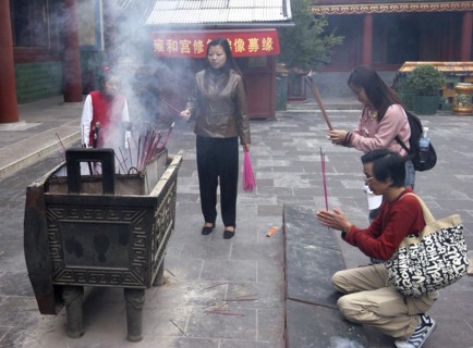 CHINA, Beijing, Lama Temple. People lighting incense during worship in the Temple courtyard
