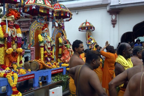 SINGAPORE, , Men and women standing beside a colourful shrine decorated with flower garlands at an