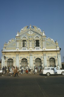 NIGERIA, Lagos, Street scene with roadside vendors ad passers by in front of mosque with pale blue