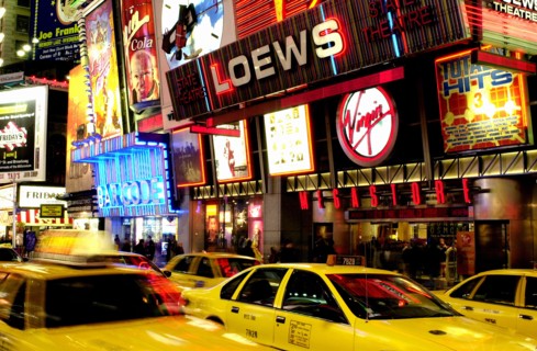 USA, New York State, New York City, Times Square illuminated at night with passing yellow taxi cabs