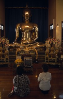 THAILAND, South, Bangkok, Wat Traimit Temple of The Golden Buddha with two women kneeling at prayer