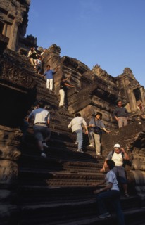 CAMBODIA, Siem Reap Province, Angkor Wat, Tourists climbing steep narrow steps to upper or third