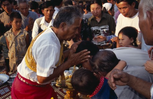 CAMBODIA, Siem Reap, Angkor Wat, Shaman at ceremony giving blessings by spraying water from his