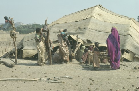 SUDAN, Tribal Peoples, Beja women and children outside tent made from woven palm matting designed