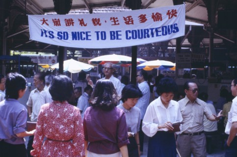 SINGAPORE, General, Street scene with mixed crowd below government banner stating Its So Nice To Be