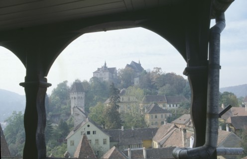 ROMANIA, Transylvania, Mures, Sighisoara.  View of town rooftops framed by archway.  Famous as